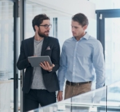 Two men discussing with laptop on their hand
